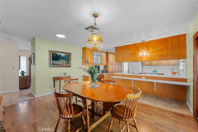 dining space with sink, light hardwood / wood-style flooring, and a textured ceiling