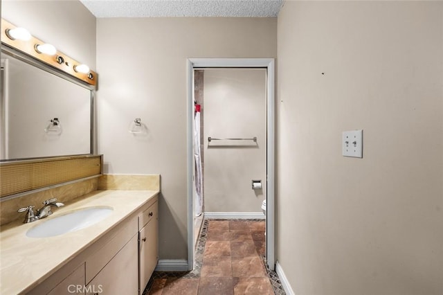 bathroom featuring vanity, a textured ceiling, and toilet