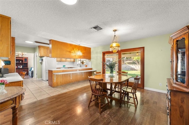 dining space with light hardwood / wood-style floors and a textured ceiling