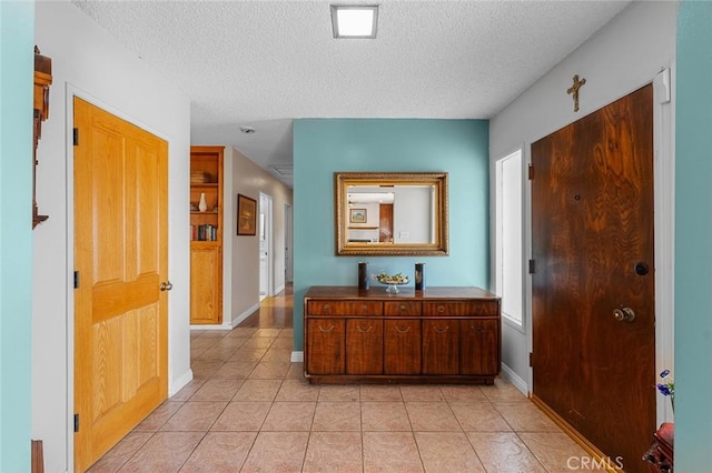 hallway featuring a textured ceiling and light tile patterned flooring