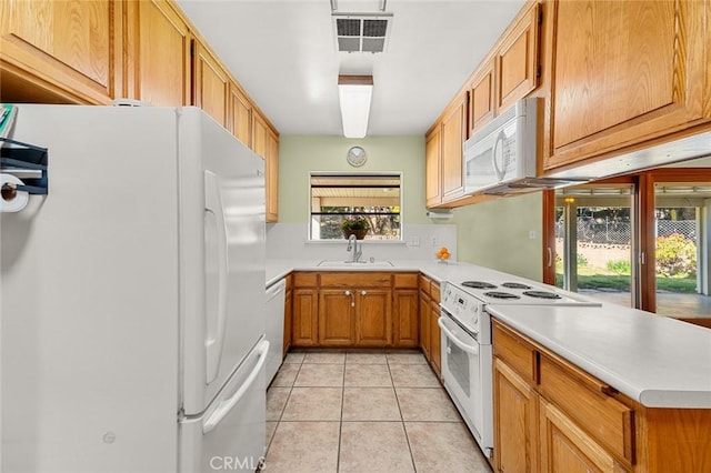 kitchen with sink, white appliances, kitchen peninsula, and light tile patterned floors