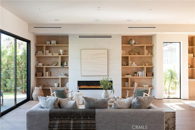 sitting room featuring built in shelves, light hardwood / wood-style flooring, and a large fireplace