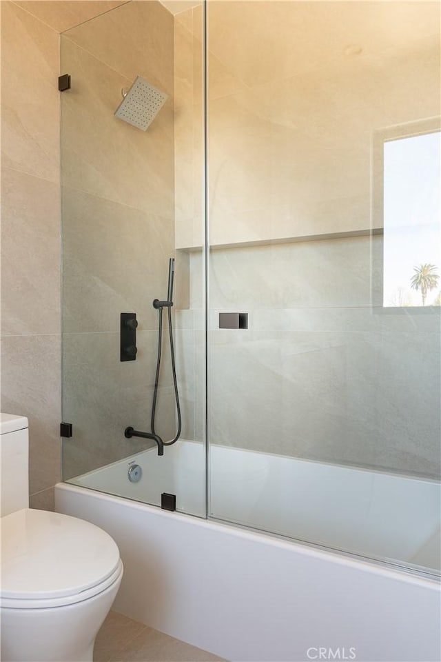 bathroom featuring enclosed tub / shower combo and toilet