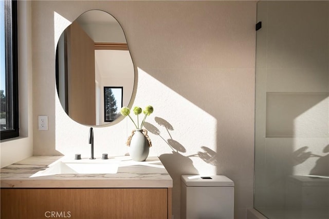 bathroom featuring vanity, walk in shower, and toilet