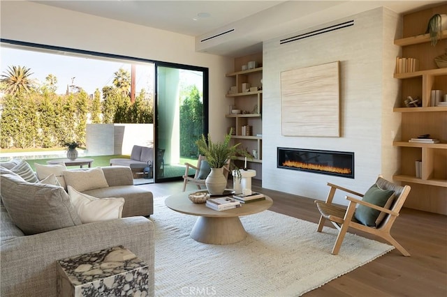 interior space with wood-type flooring, a large fireplace, and built in features