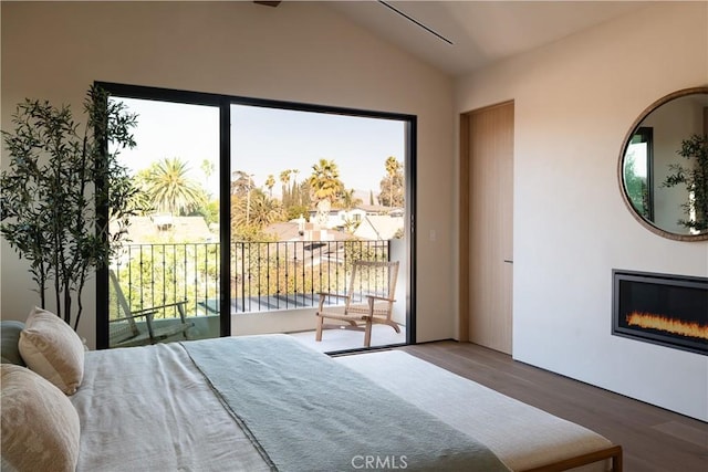 bedroom featuring access to exterior, hardwood / wood-style flooring, and vaulted ceiling