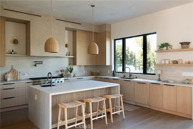 kitchen featuring dark wood-type flooring, sink, a breakfast bar area, a kitchen island with sink, and backsplash