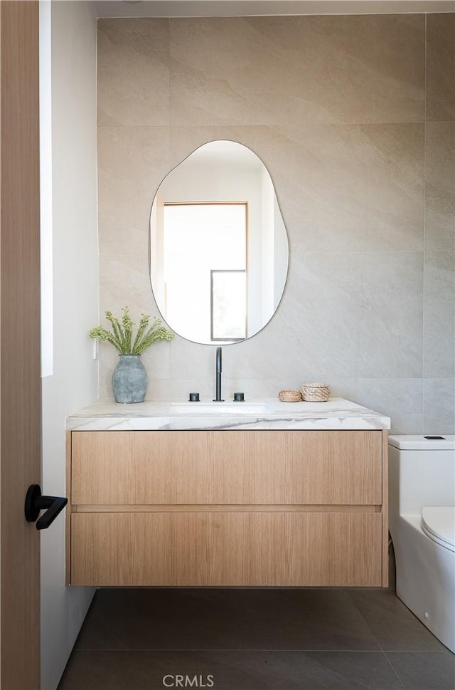 bathroom featuring vanity, tile patterned flooring, tile walls, and toilet