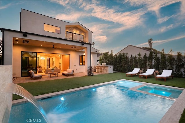 back house at dusk with an outdoor bar, ceiling fan, a patio, an outdoor living space, and a pool with hot tub