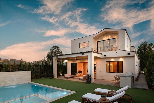 back house at dusk with an outdoor bar, ceiling fan, outdoor lounge area, a patio area, and a balcony