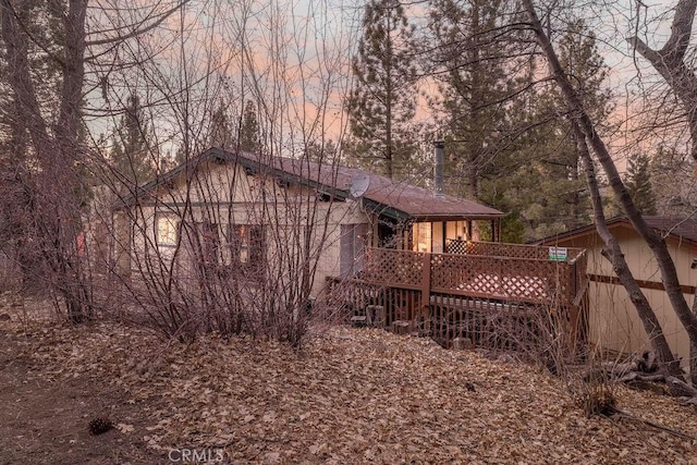 back house at dusk with a wooden deck