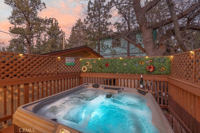 pool at dusk featuring a hot tub