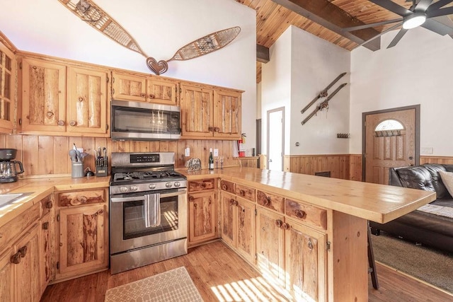 kitchen with appliances with stainless steel finishes, beam ceiling, high vaulted ceiling, wooden ceiling, and light wood-type flooring