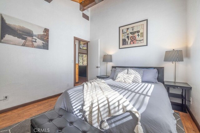 bedroom featuring hardwood / wood-style floors and beamed ceiling