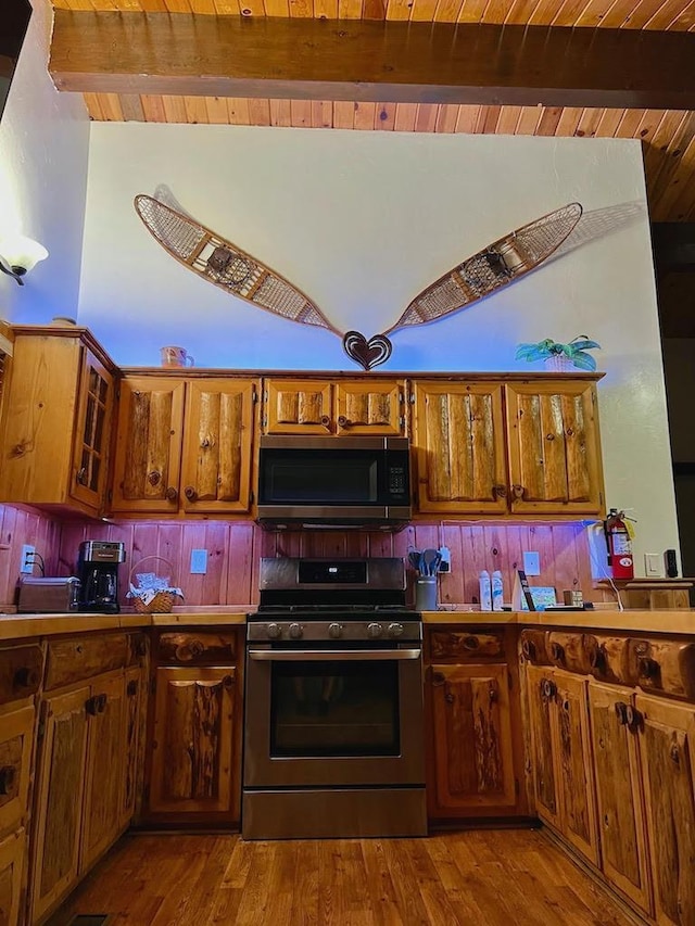 kitchen featuring lofted ceiling with beams, wood ceiling, appliances with stainless steel finishes, and light hardwood / wood-style floors