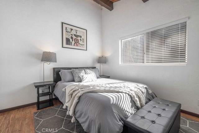 bedroom with dark hardwood / wood-style floors and beam ceiling