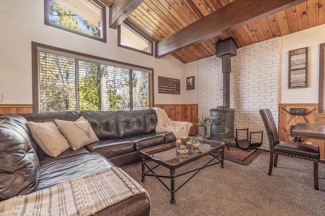 living room with wood walls, wood ceiling, a wood stove, beam ceiling, and carpet