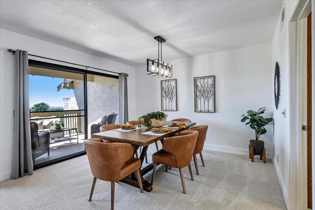 carpeted dining space featuring a notable chandelier