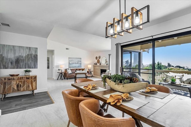 dining area with vaulted ceiling, carpet, and a fireplace