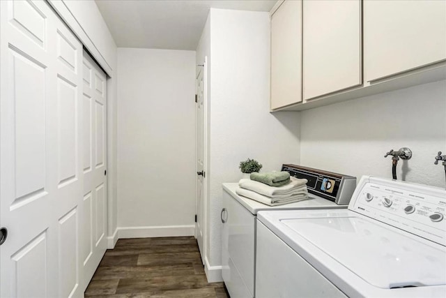 clothes washing area featuring cabinets, washing machine and clothes dryer, and dark hardwood / wood-style floors