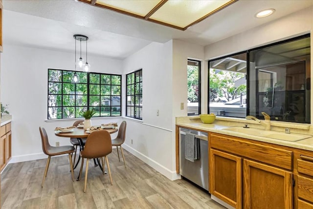 kitchen with stainless steel dishwasher, sink, hanging light fixtures, and a wealth of natural light