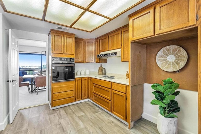 kitchen featuring white electric cooktop, black oven, and light wood-type flooring