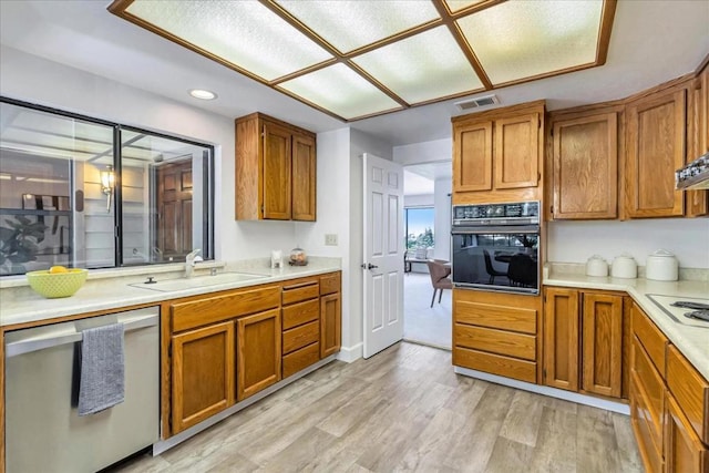 kitchen featuring white stovetop, black oven, dishwasher, sink, and light hardwood / wood-style floors