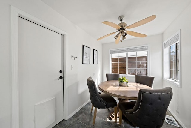 dining area featuring ceiling fan and dark tile patterned flooring