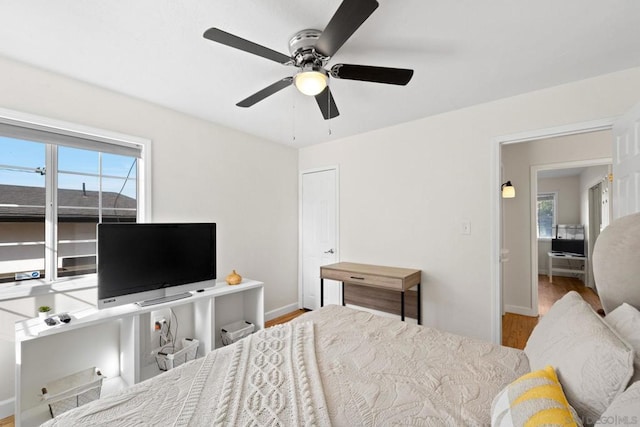 bedroom with multiple windows, hardwood / wood-style flooring, and ceiling fan