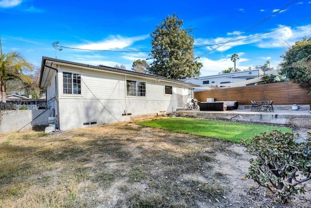 back of house featuring outdoor lounge area, a patio, and a lawn