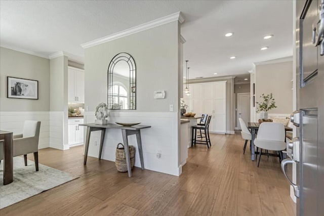 kitchen featuring a kitchen bar, white cabinetry, crown molding, kitchen peninsula, and hardwood / wood-style flooring