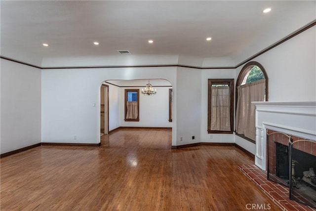 unfurnished living room featuring hardwood / wood-style flooring, a tile fireplace, and a notable chandelier