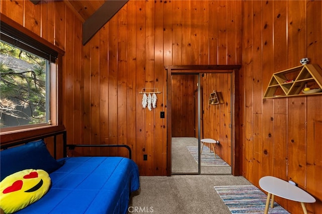 carpeted bedroom featuring a closet and wood walls