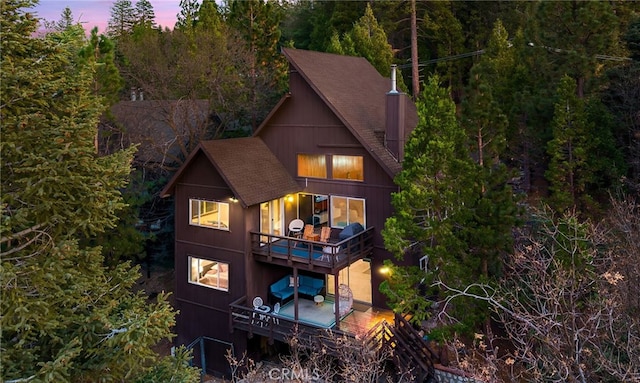 back house at dusk featuring a balcony