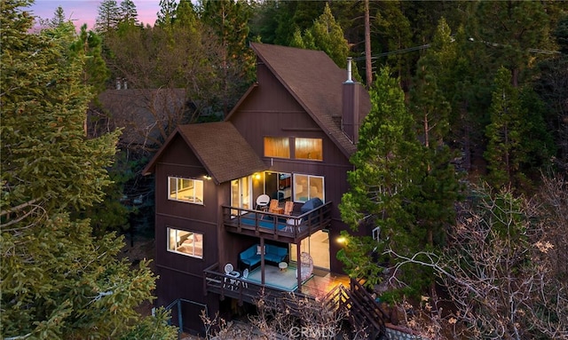 back of property at dusk with roof with shingles