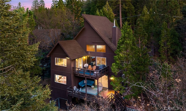 rear view of property with a wooden deck, a balcony, and roof with shingles