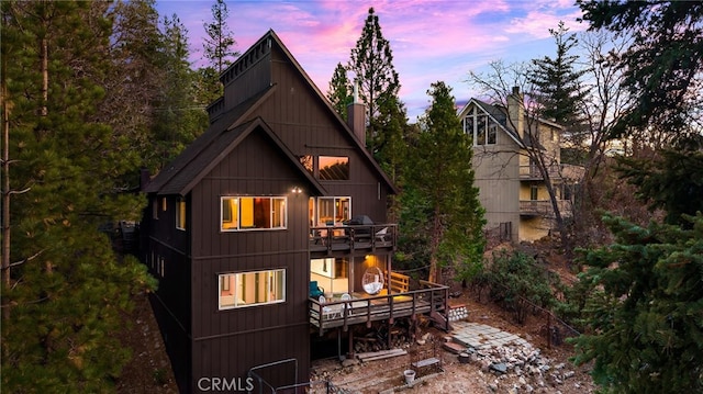 back of house at dusk with a balcony and a deck