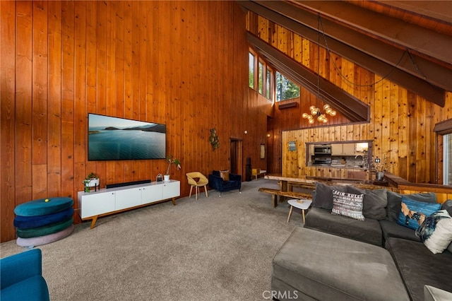 carpeted living room featuring beam ceiling, wooden walls, and a high ceiling