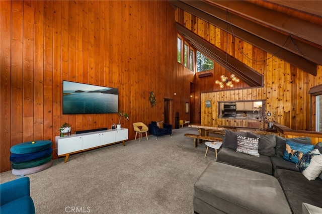 carpeted living room with wooden walls, high vaulted ceiling, and beam ceiling