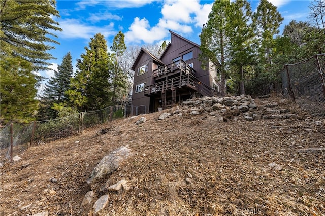 rear view of house featuring a deck, stairway, and fence