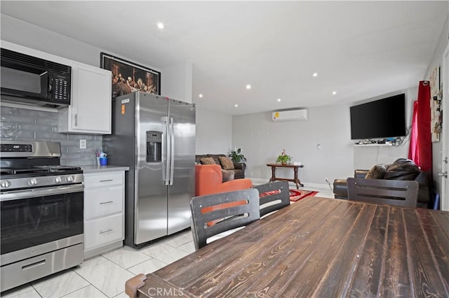 kitchen with white cabinetry, decorative backsplash, stainless steel appliances, and a wall unit AC