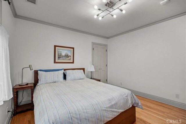 bedroom featuring hardwood / wood-style flooring, ornamental molding, and a barn door