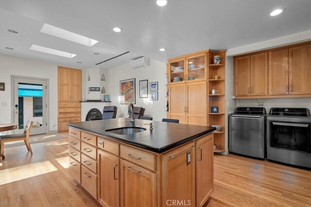 kitchen with an island with sink, separate washer and dryer, sink, and light hardwood / wood-style floors