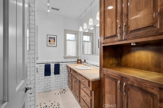 bathroom with walk in shower, tile patterned floors, tile walls, and vanity