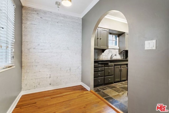 bathroom featuring brick wall, ornamental molding, and hardwood / wood-style floors