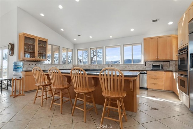 kitchen with lofted ceiling, a kitchen bar, a kitchen island, and light tile patterned floors