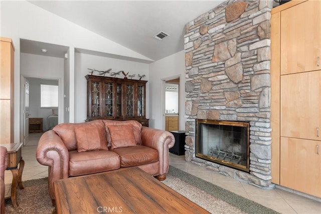 living room featuring lofted ceiling, a fireplace, and light tile patterned floors