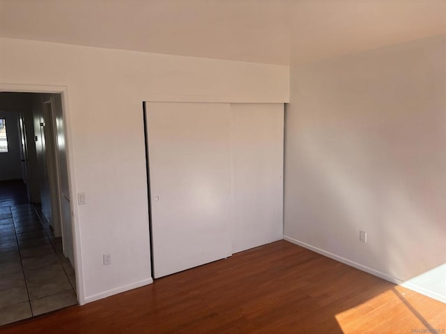 unfurnished bedroom with dark wood-type flooring and a closet