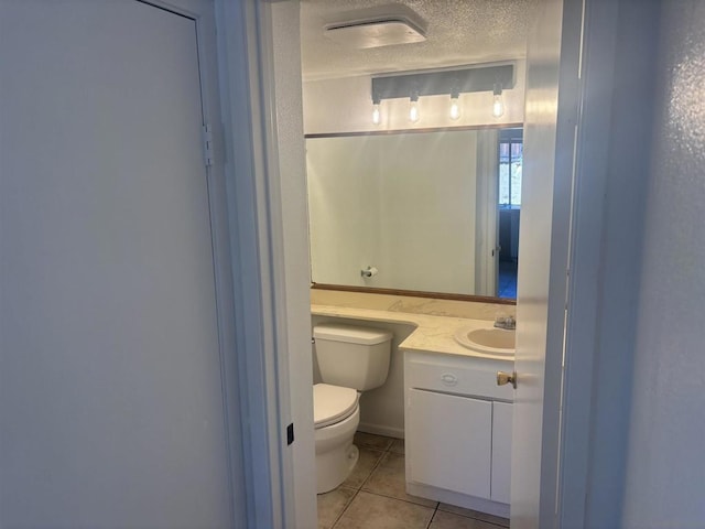 bathroom featuring tile patterned flooring, vanity, a textured ceiling, and toilet