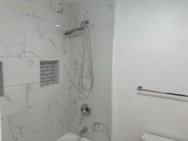 bathroom featuring toilet and tiled shower / bath combo